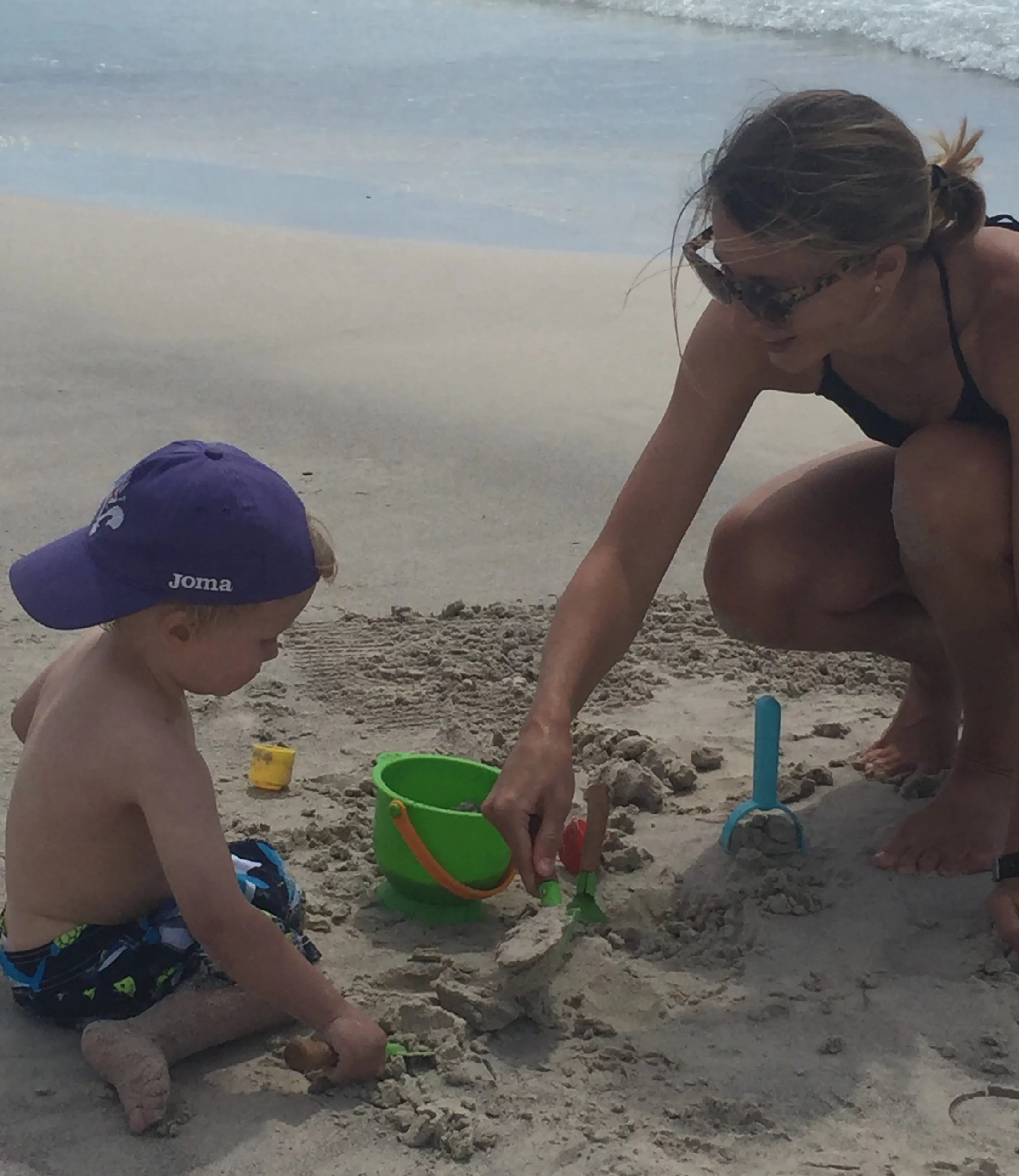 boy and mother playing in sand at beach