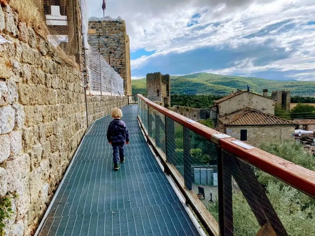 Boy walking on pathway along the medieval walls of Monterrigioni in Italy.