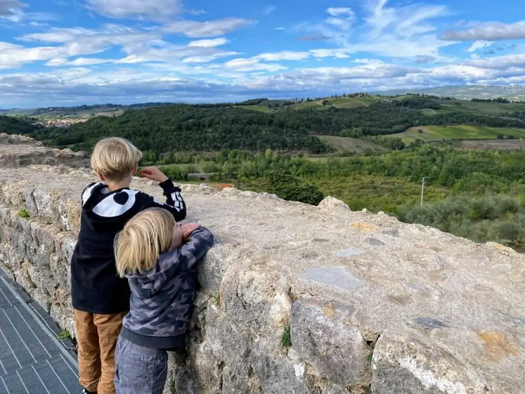 Two young boys are on the Monteriggioni, Italy walls looking out over the view of the countryside.