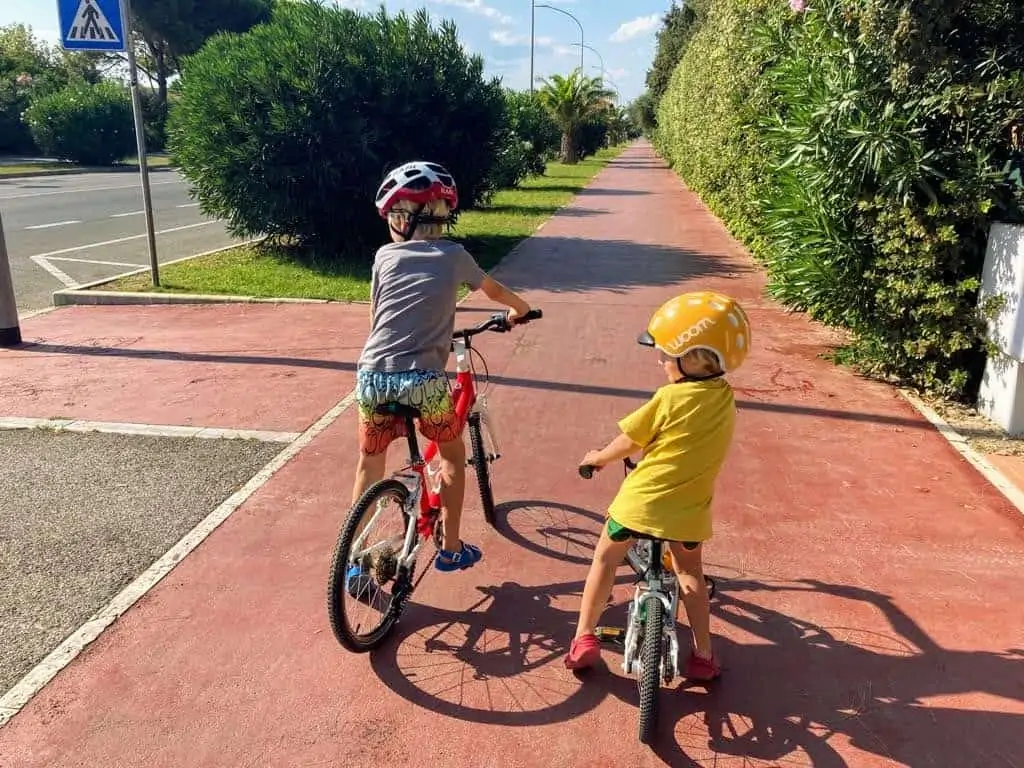 two kids riding bicycles on the beach bike path in forte dei marmi, italy