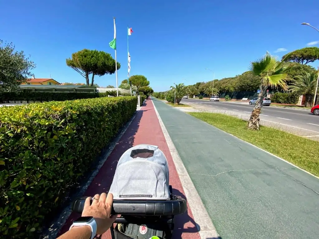 hand pushing stroller on bike path in forte dei marmi, italy