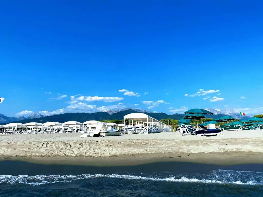forte dei marmi beach with beach umbrellas and the mountains in the background