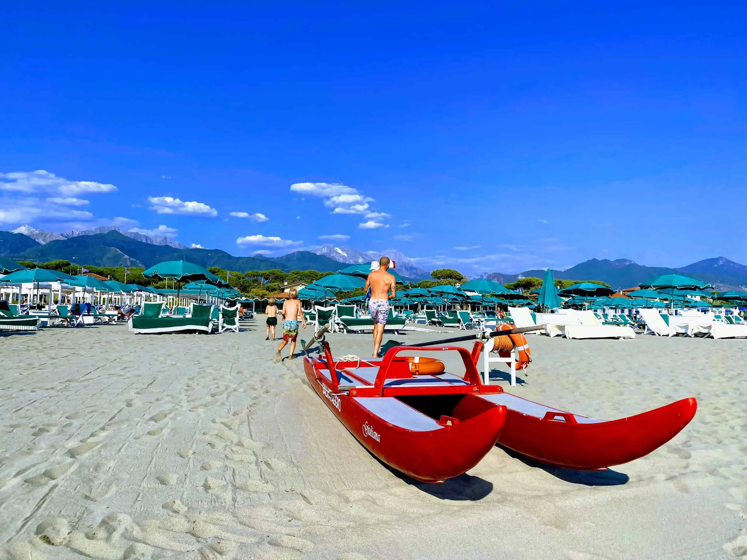 Beach with red lifeguard boat on sand in forte dei marmi, italy.