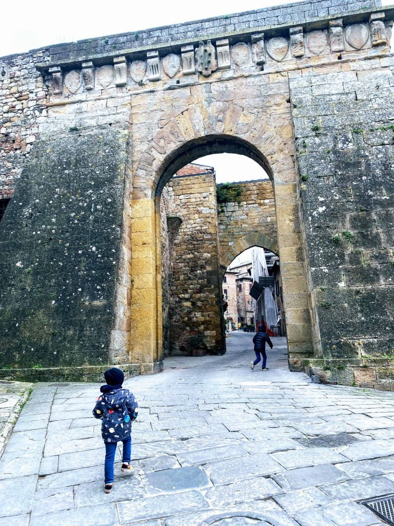 Boys walking through the archway of the Porta al Prato in Montepulciano Italy.