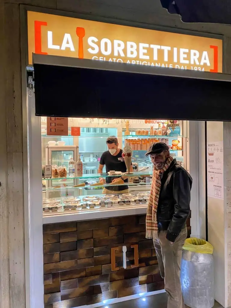 Man standing in front of La Sorbettiera gelateria storefront in Florence, Italy.