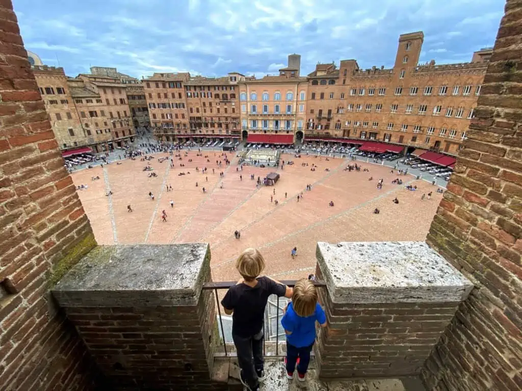 Boys looking down at the Piazza del Campo in Siena, Italy from a viewpoint on the Torre del Mangia.