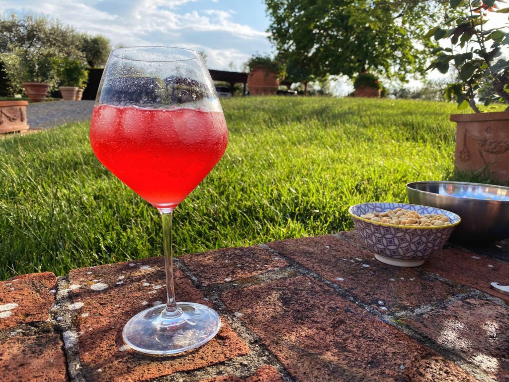 Campari spritz sitting on a terracotta ledge in a garden at a home in Tuscany, Italy.