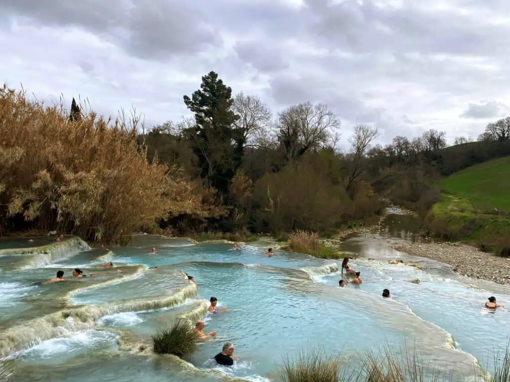 A few people sitting in the pools of the Saturnia hot springs (Cascate del Mulino) in southern Tuscany, Italy.  