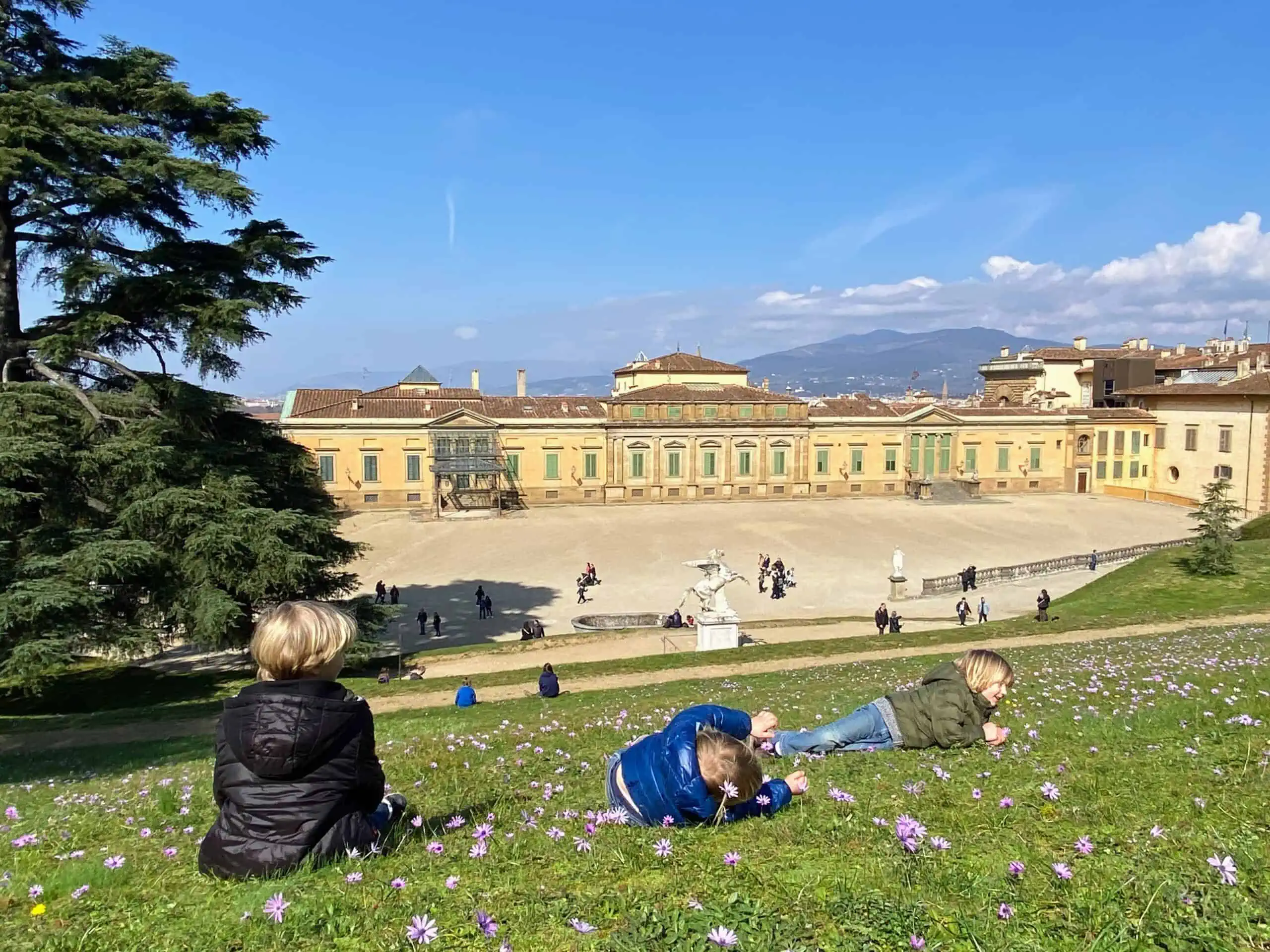 Boys sitting on grass overlooking the back of Palazzo Pitti in Florence, Italy.