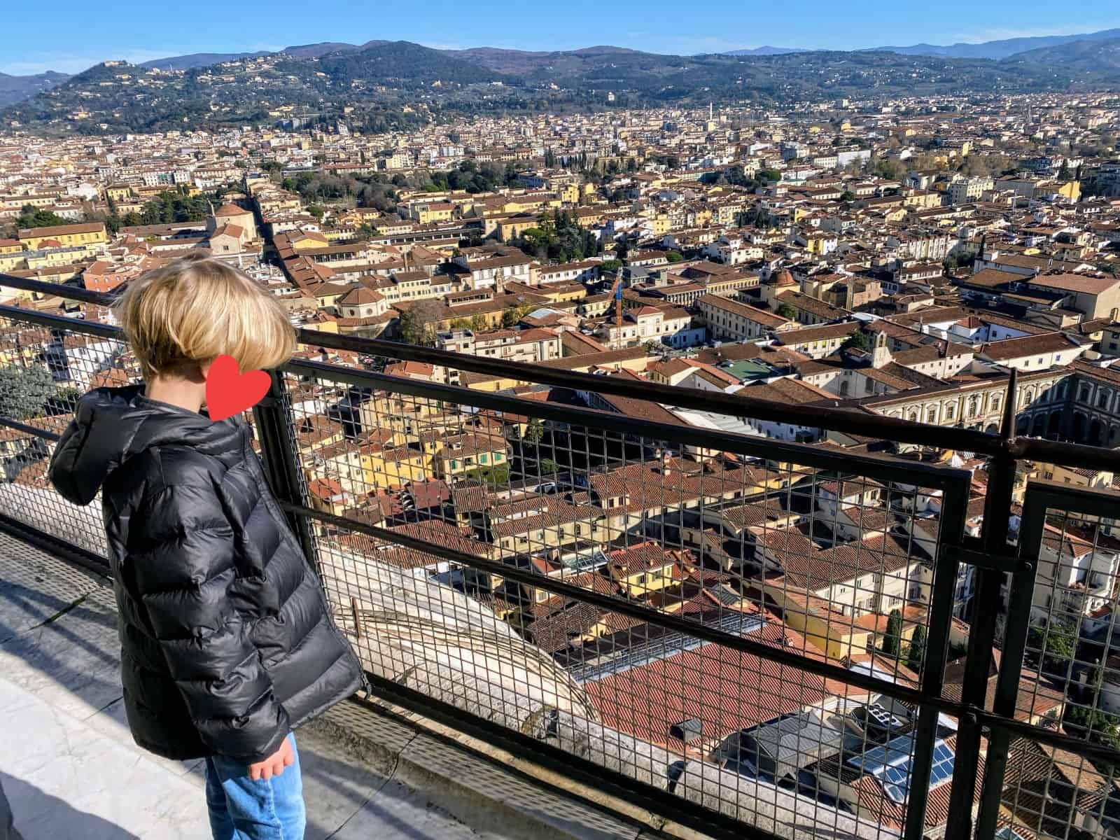 Boy looking at the view of Florence from the top of the Duomo climb. His face is covered with a red graphic heart.