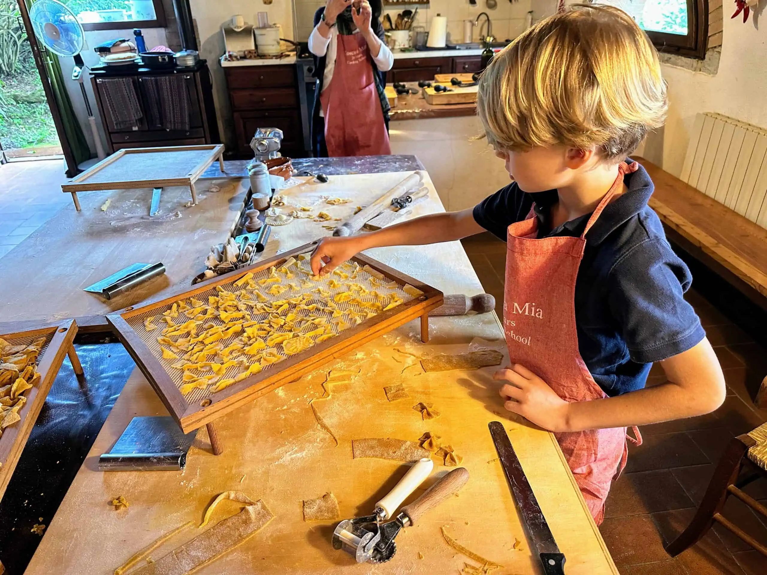 Boy making fresh pasta shapes and setting them on a drying rack at a cooking class.