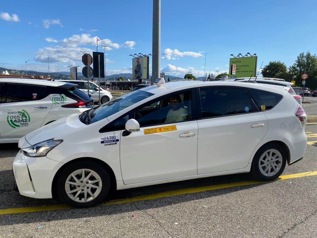 Taxi driver sitting in car in a parking lot in Italy. Driver looking at photographer.