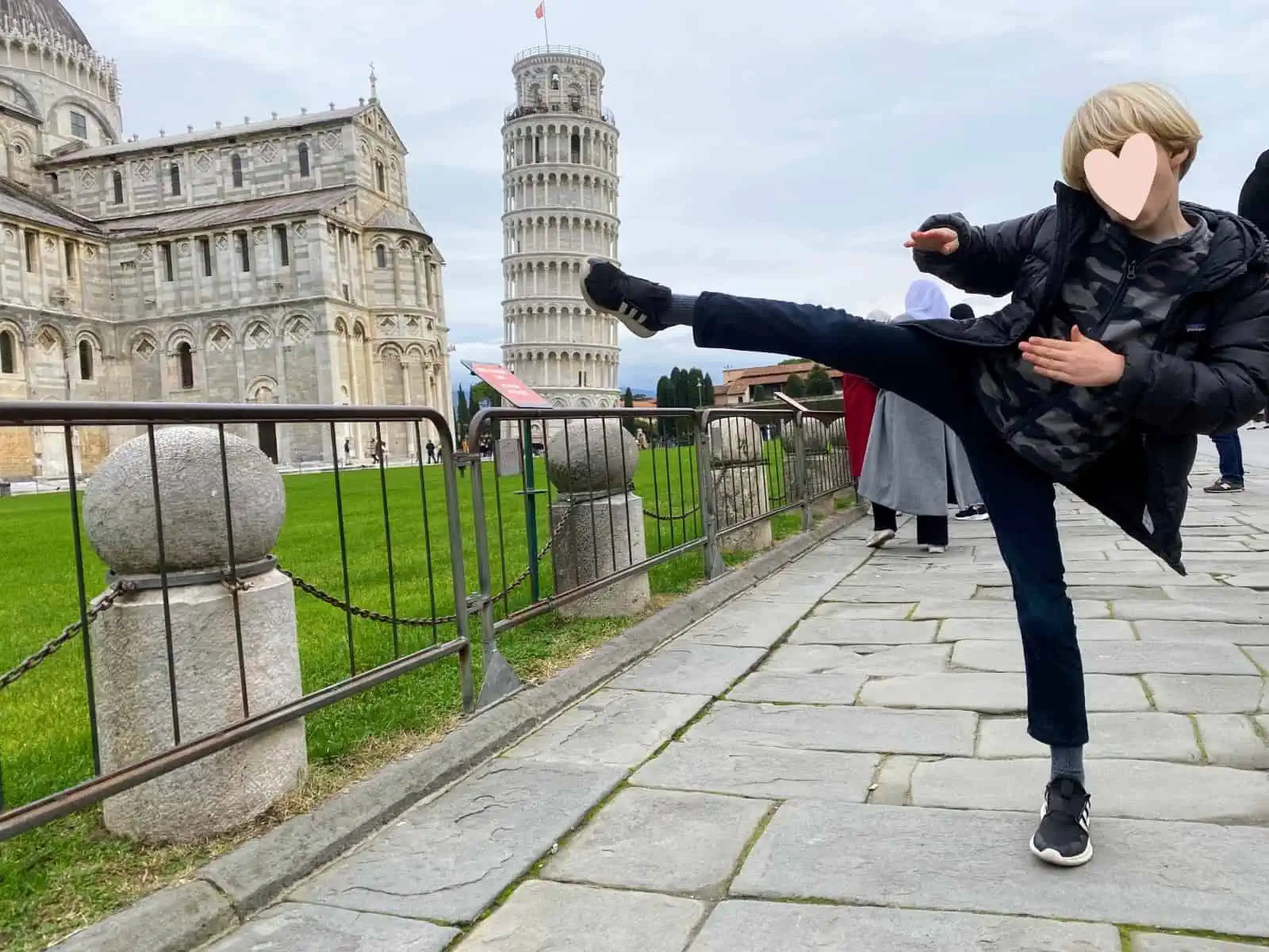 Boy pretending to kick Leaning Tower of Pisa.