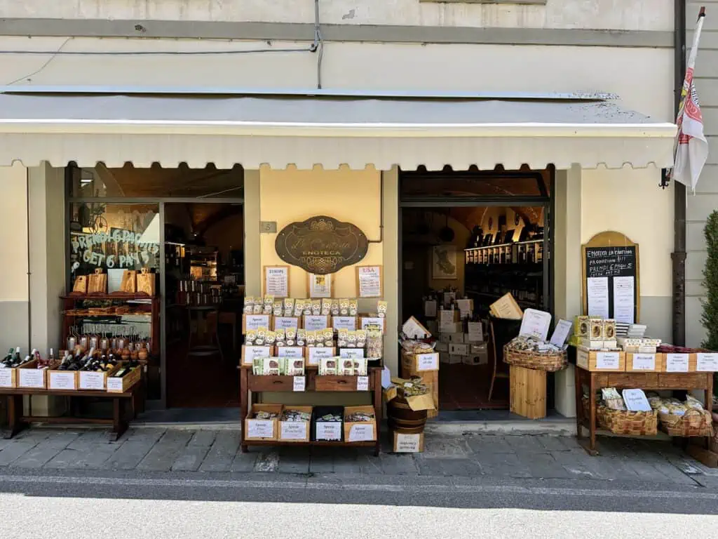 Front entrance to enoteca and food souvenir shop in Castellina in Chianti, Italy. There are displays set up outside the shop.