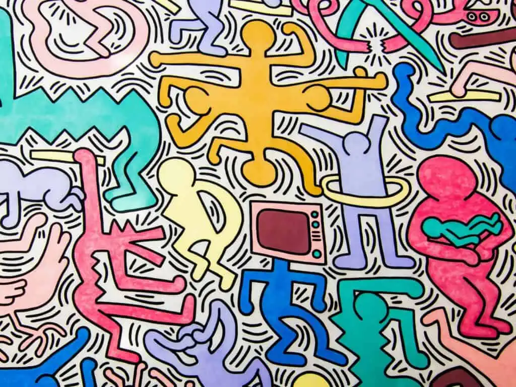 Close up of Keith Haring's Tuttomondo mural in Pisa, Italy. Colorful cartoon outlines, one with a television head and another holding a baby.
