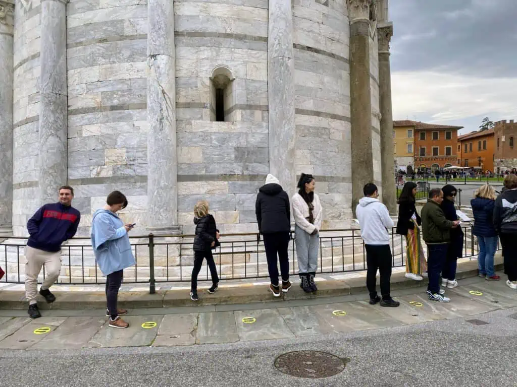 People waiting in line at the base of the Leaning Tower of Pisa.