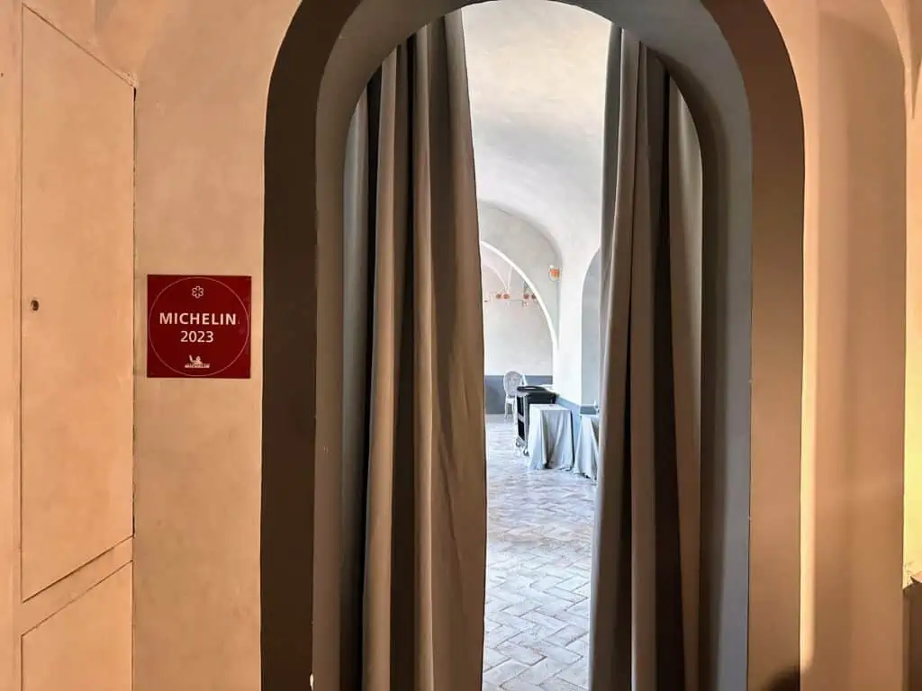 Curtained entrance to restaurant La Torre in Tavarnelle in Tuscany, Italy. Red Michelin 2023 sign on left.