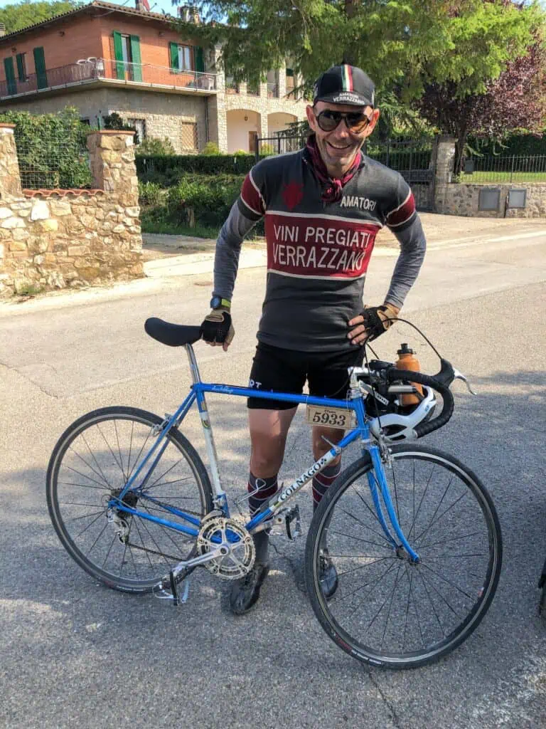 Man wearing vintage bicycle gear standing with a vintage bike in Gaiole in Chianti.