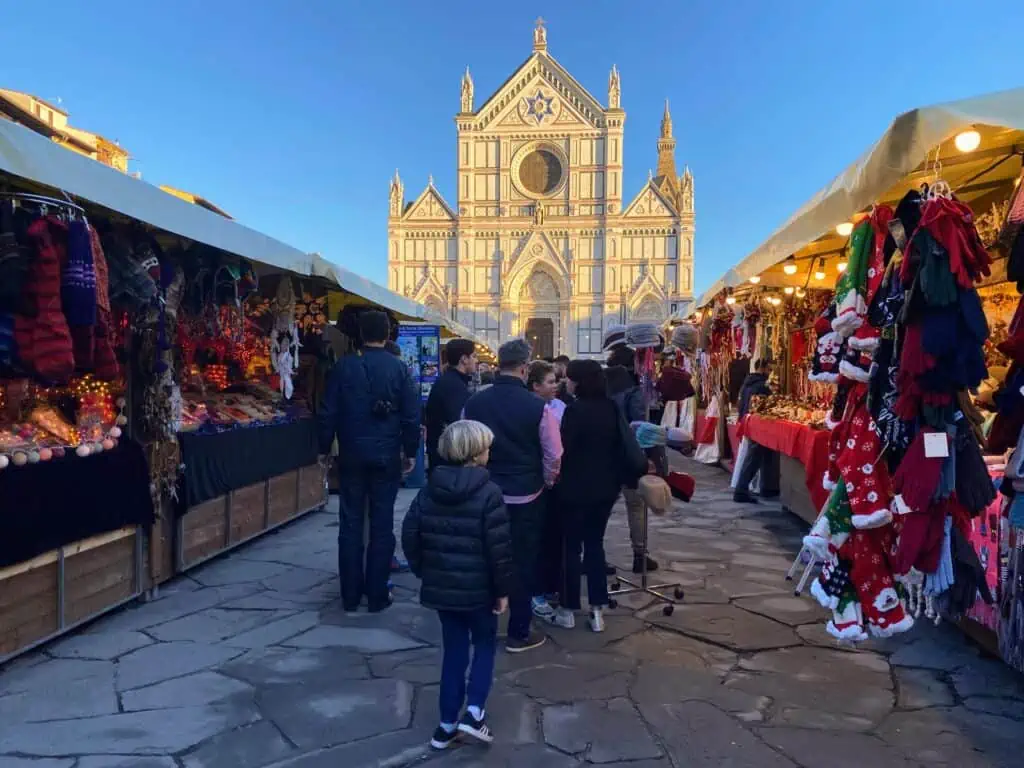 Boy walking between stalls at Florence, Italy Christmas market. You can see Santa Croce church in background.