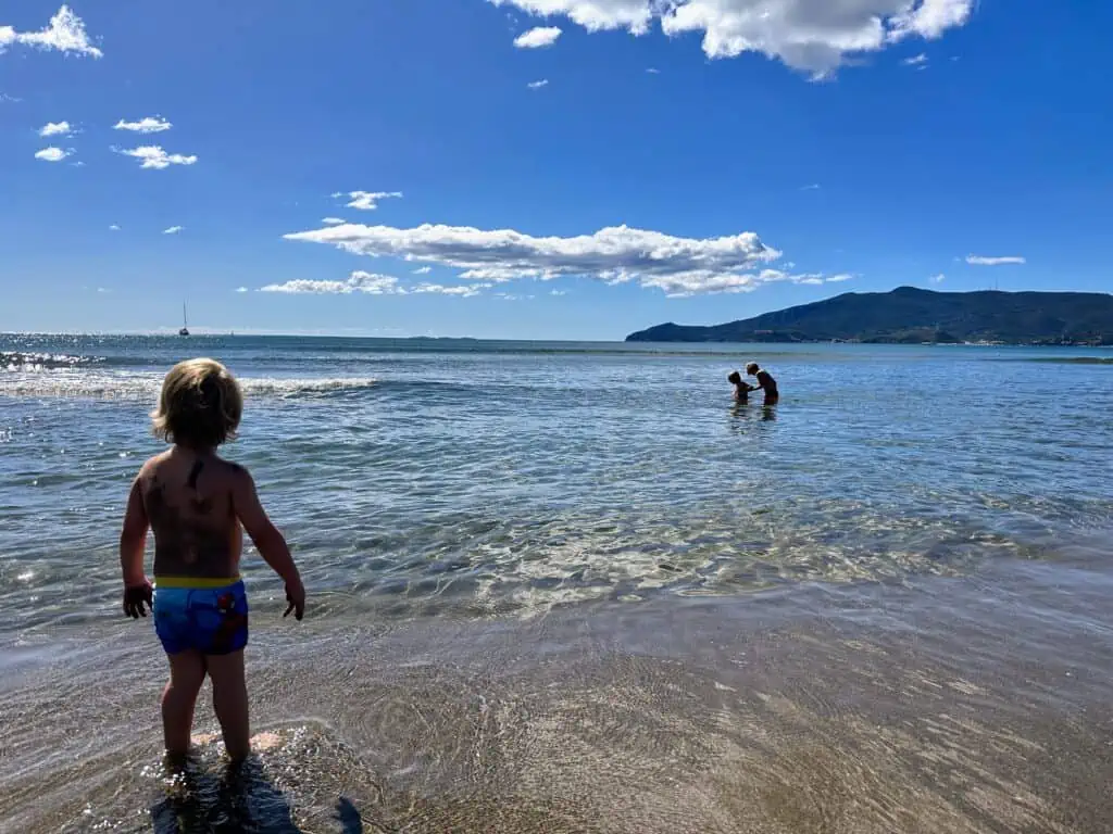 Boys playing in the water at Feniglia beach in Tuscany.