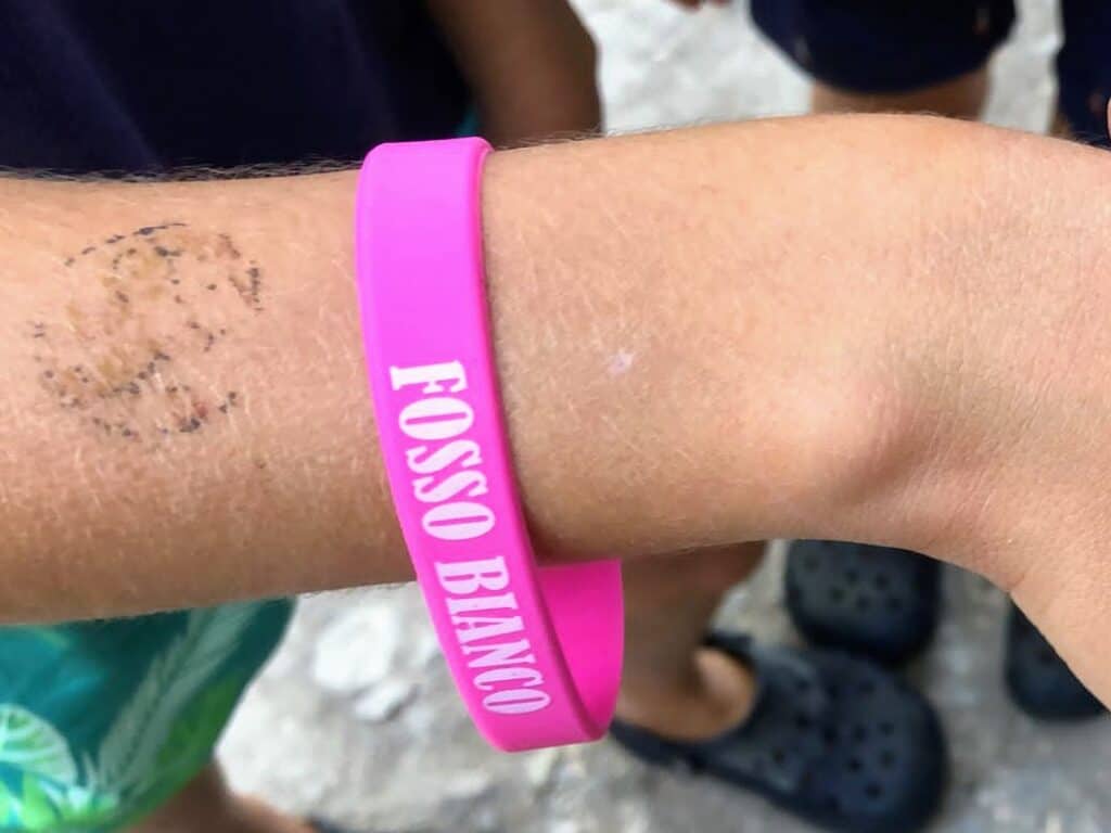 Pink bracelet that says 'Fosso Bianco' on a wrist.