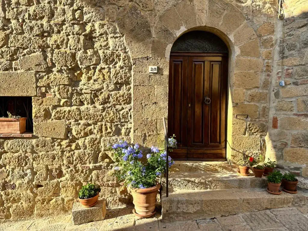 Front of old stone building in Tuscany. Late afternoon light shines on the stone walls and the potted plants decorating the front entrance.