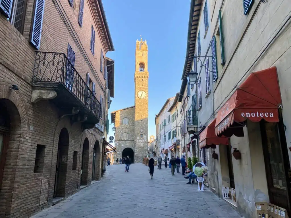 Piazza in Montalcino, Italy. You can see shops on either side and the main clock tower at the far end of the piazza.