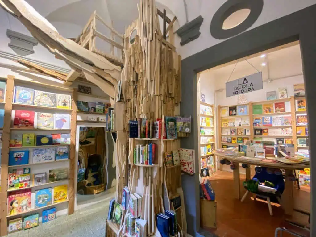 Inside a children's bookshop in Florence, Italy. There's a wooden puzzle tree in the middle and themed rooms on either side.