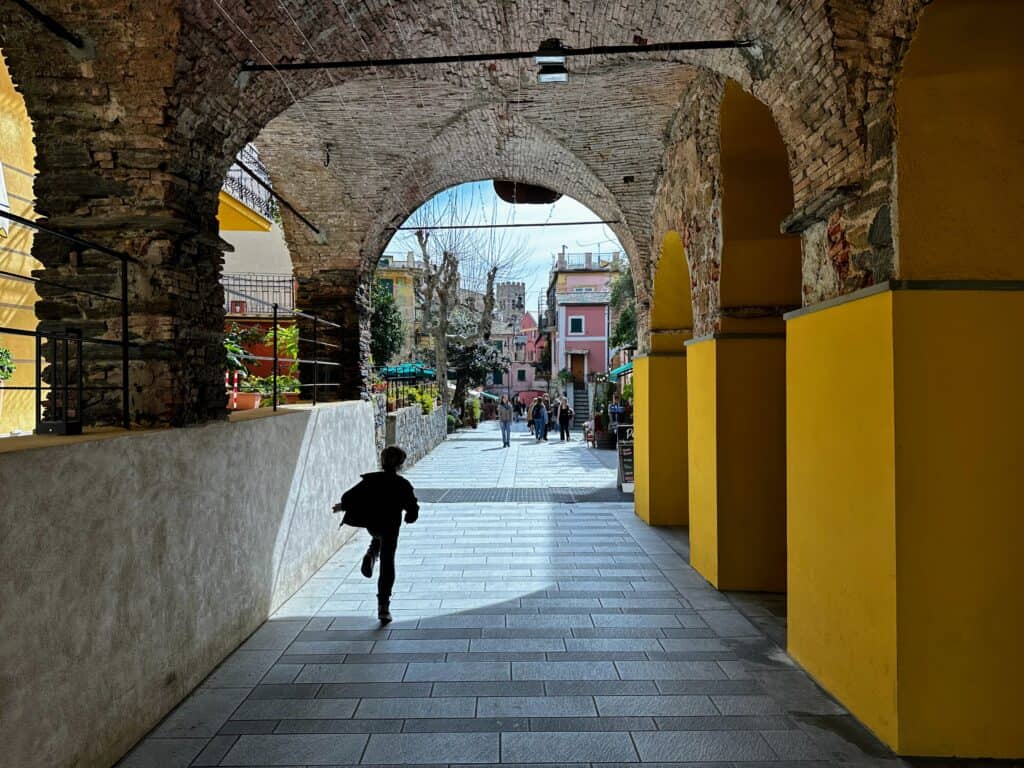 Boy runs through archway in Monterosso al Mare in the Cinque Terre, Italy.