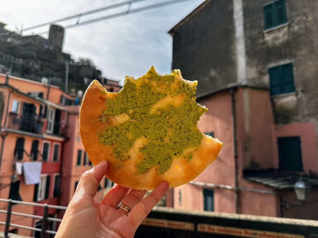 Hand holds up bread with pesto in a village in the Cinque Terre in Italy.