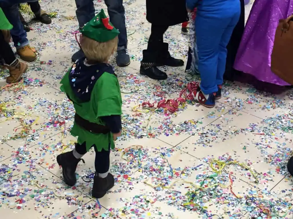 Boy dressed as Peter Pan walks through confetti at a Carnevale celebration in Italy.