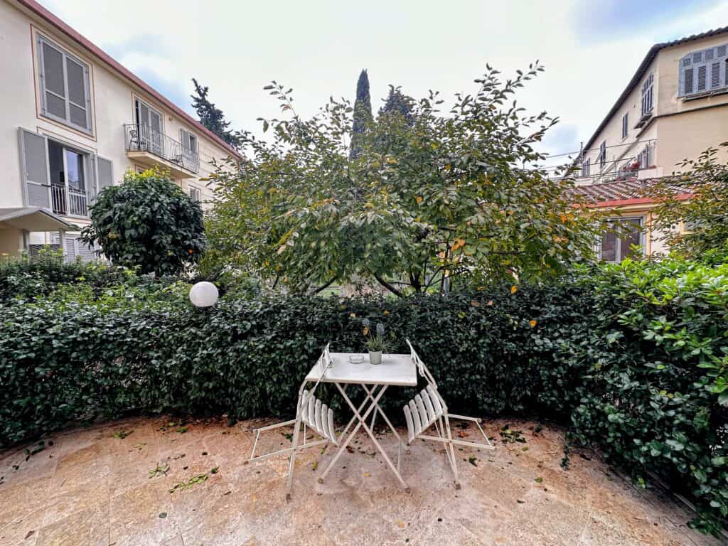 Tiled terrace surrounded by bushes in an apartment complex in Florence, Italy.