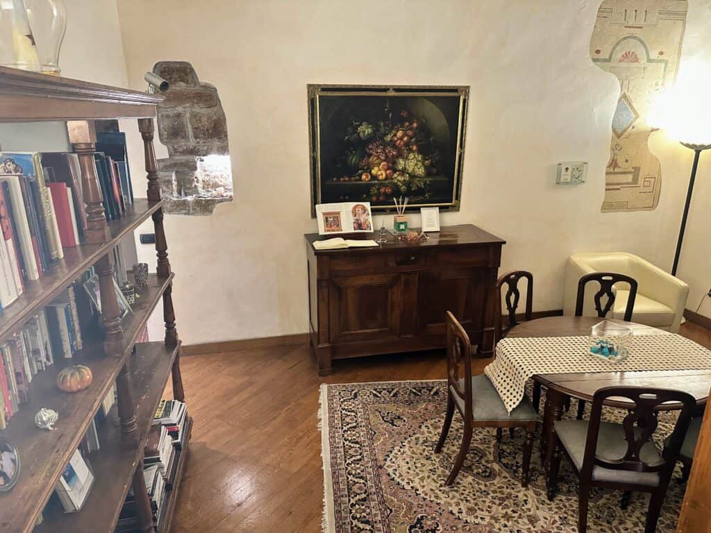 Common area with bookshelf on left, table and chairs on right, and wooden furniture on back wall. This is a common area in a hotel in Piazza della Signoria in Florence, Italy.