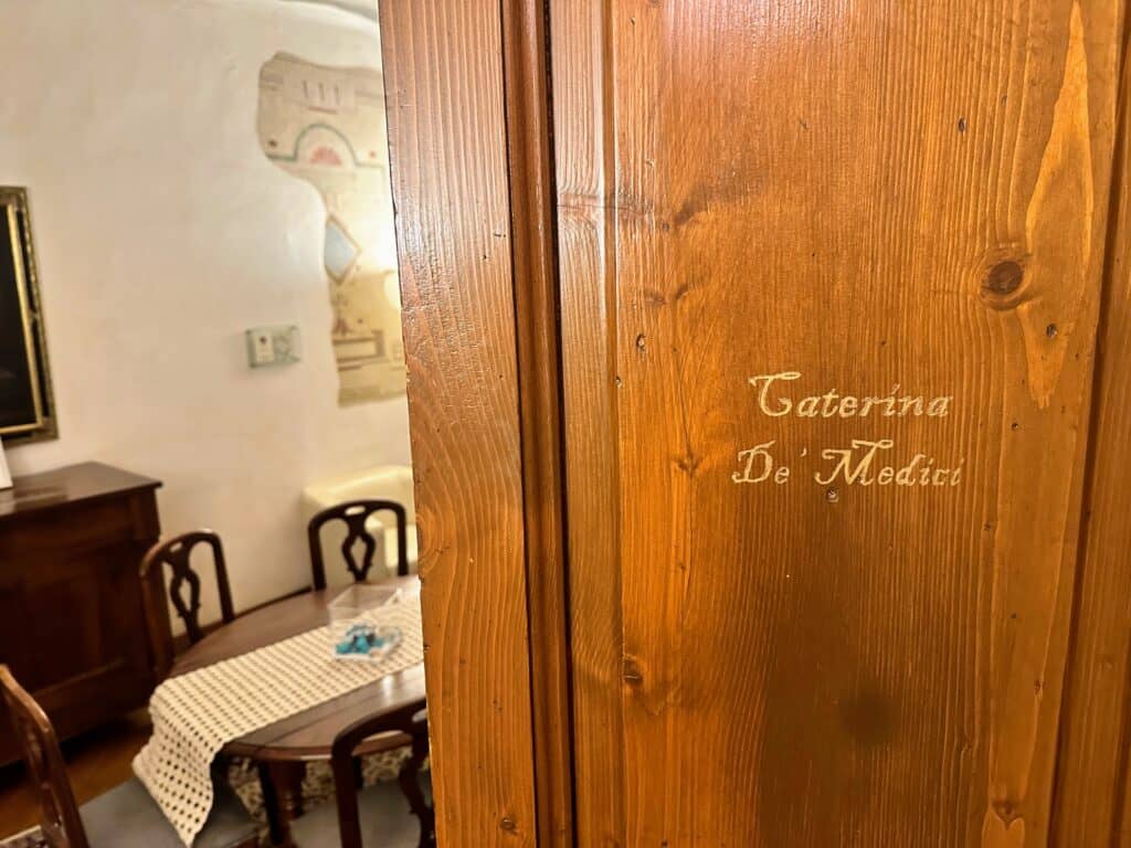 Wooden door with 'Caterina de' Medici' in cursive writing. Wooden table on left.