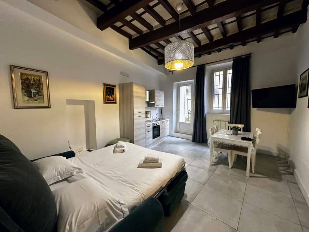 Sofabed, dining area, and small kitchen in a light-filled apartment in Florence, Italy.