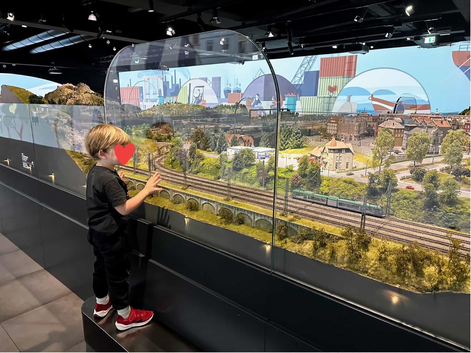 Boy looks at the HZERO train museum display from behind plexiglass.