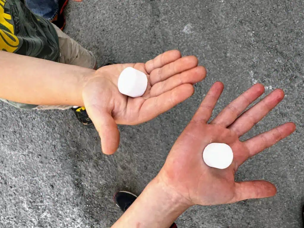 Two children hold salt tablets in the palms of their hands above the pavement at the Volterra salt works in Tuscany, Italy.
