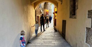 Family walking through archway in small village in Italy (Capalbio).