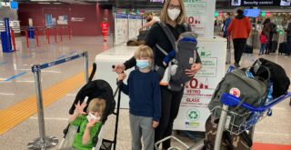 Woman standing with boys and luggage at airport.